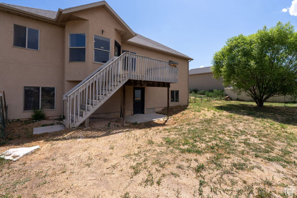 Back of property featuring stucco siding, stairway, and a deck