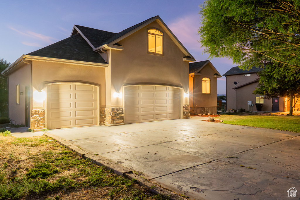Traditional-style home featuring concrete driveway, stucco siding, a yard, roof with shingles, and an attached garage