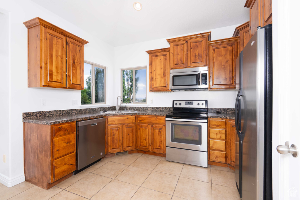 Kitchen featuring stainless steel appliances, brown cabinets, and dark countertops