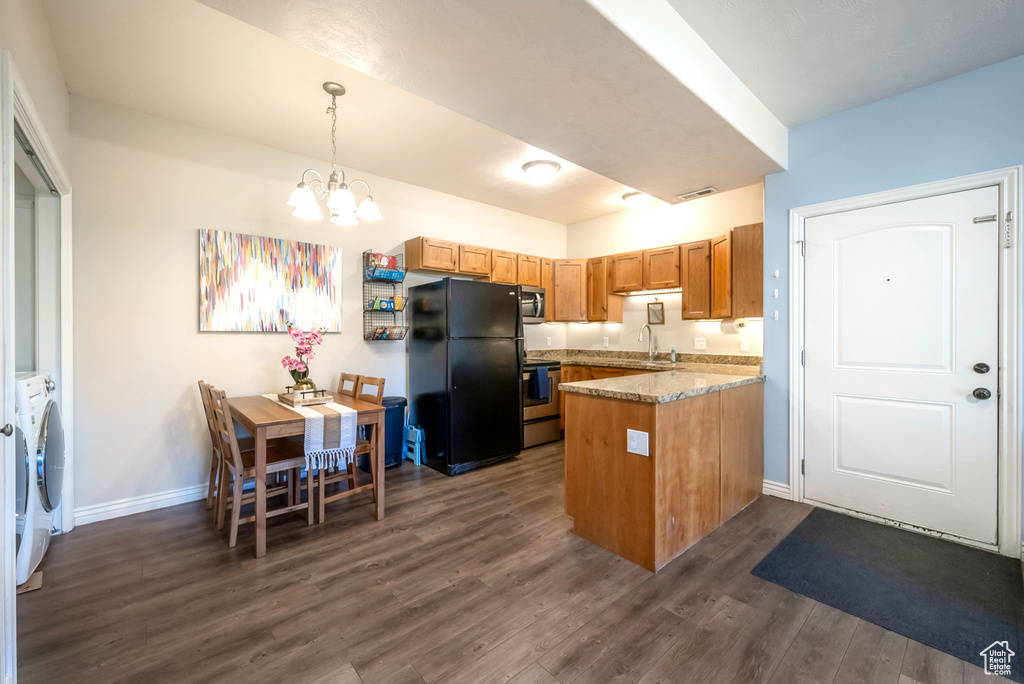 Kitchen with washer and dryer, a peninsula, appliances with stainless steel finishes, a chandelier, and dark wood-style floors