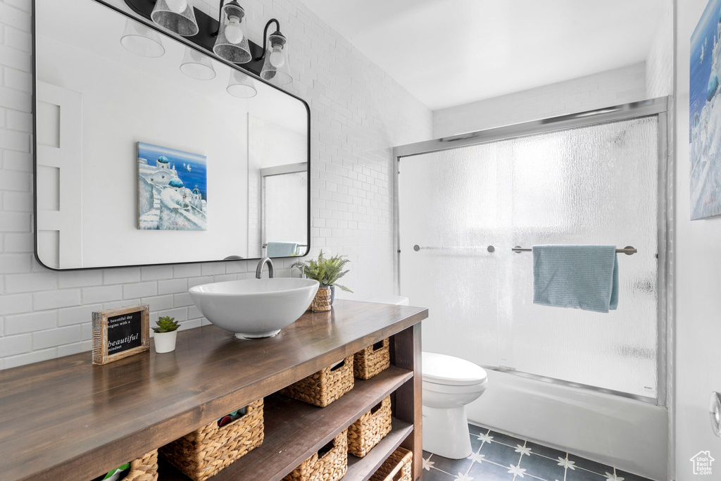 Bathroom featuring a shower with door, vanity, tile patterned floors, and decorative backsplash