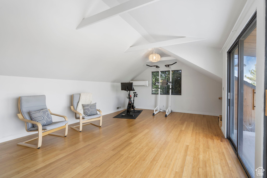 Exercise room with light wood finished floors and lofted ceiling