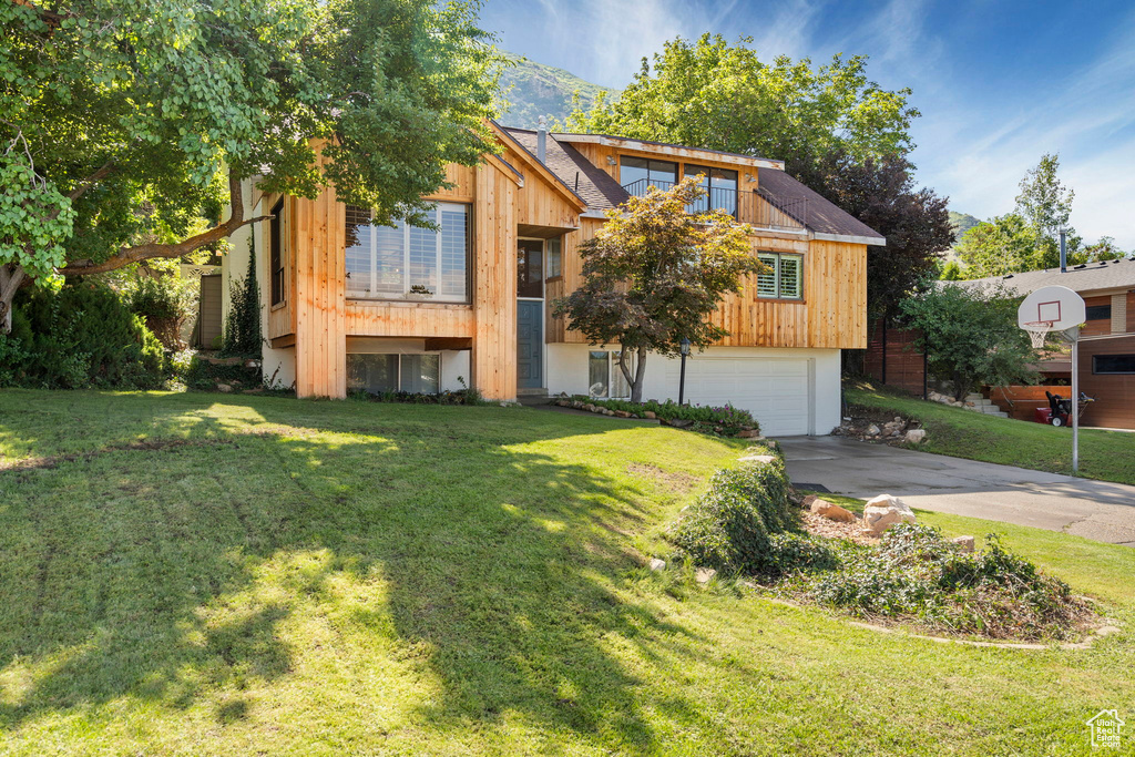 View of front of home with an attached garage, a front lawn, and concrete driveway