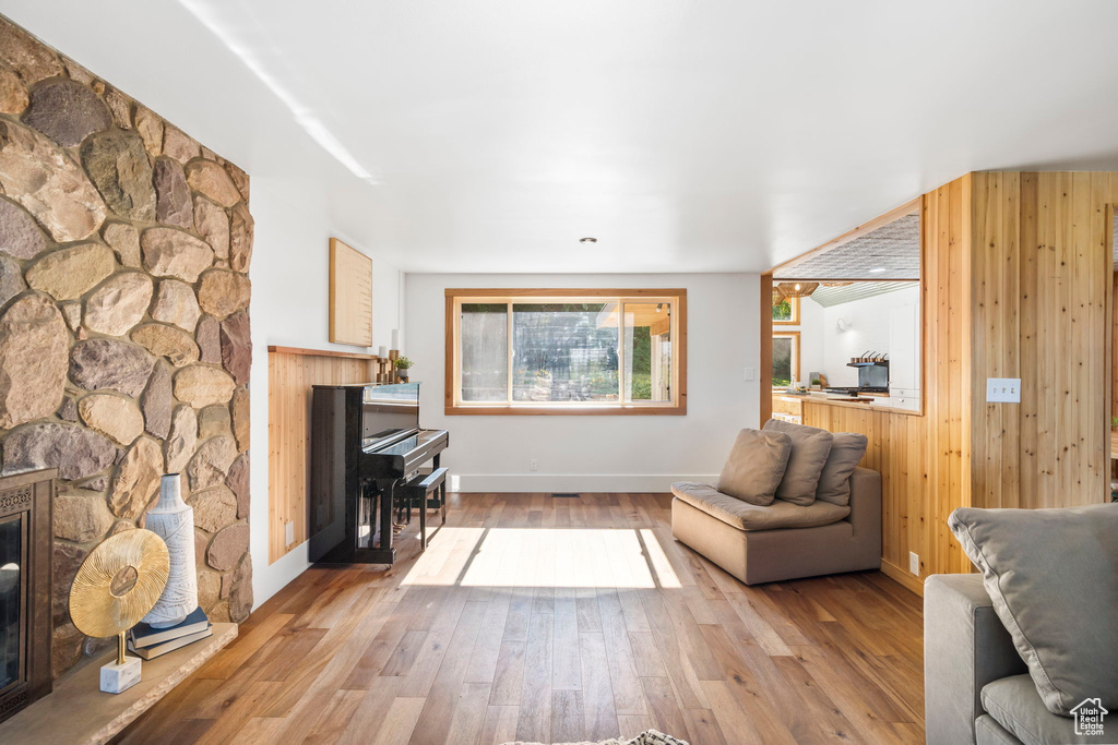 Living area with a fireplace, wood finished floors, and wooden walls