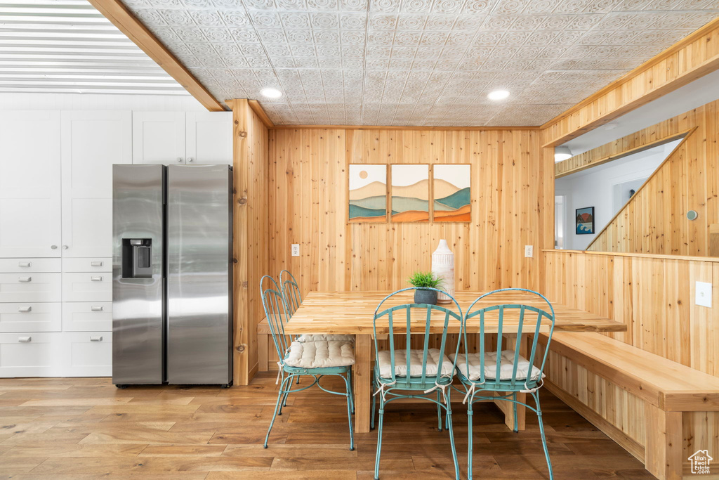 Dining area featuring wood walls, recessed lighting, and light wood-style floors