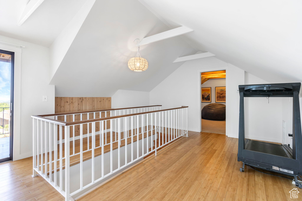 Corridor featuring lofted ceiling, wood finished floors, and an upstairs landing