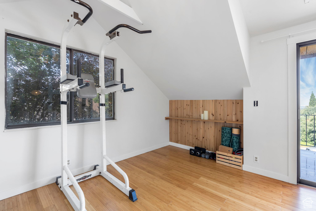 Exercise area with plenty of natural light, wood finished floors, wooden walls, and lofted ceiling