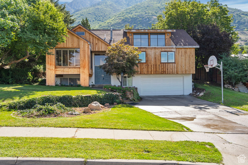 View of front of property with a mountain view, a front yard, driveway, and a garage