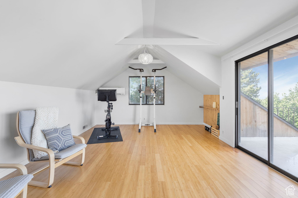 Workout area with light wood-type flooring and vaulted ceiling