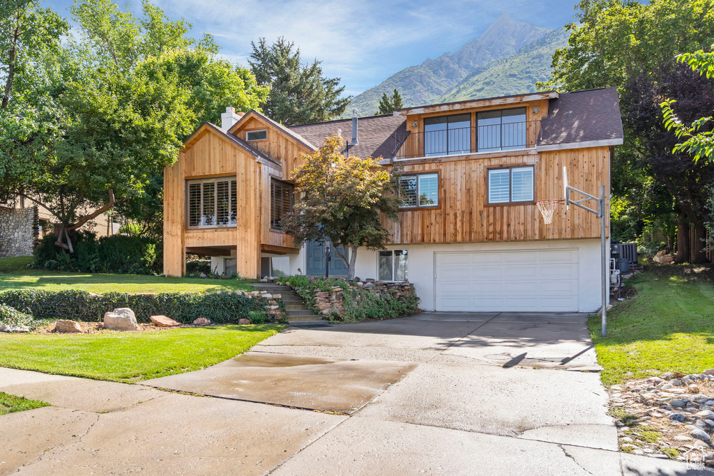 View of front of house with driveway, a mountain view, a front yard, and a garage