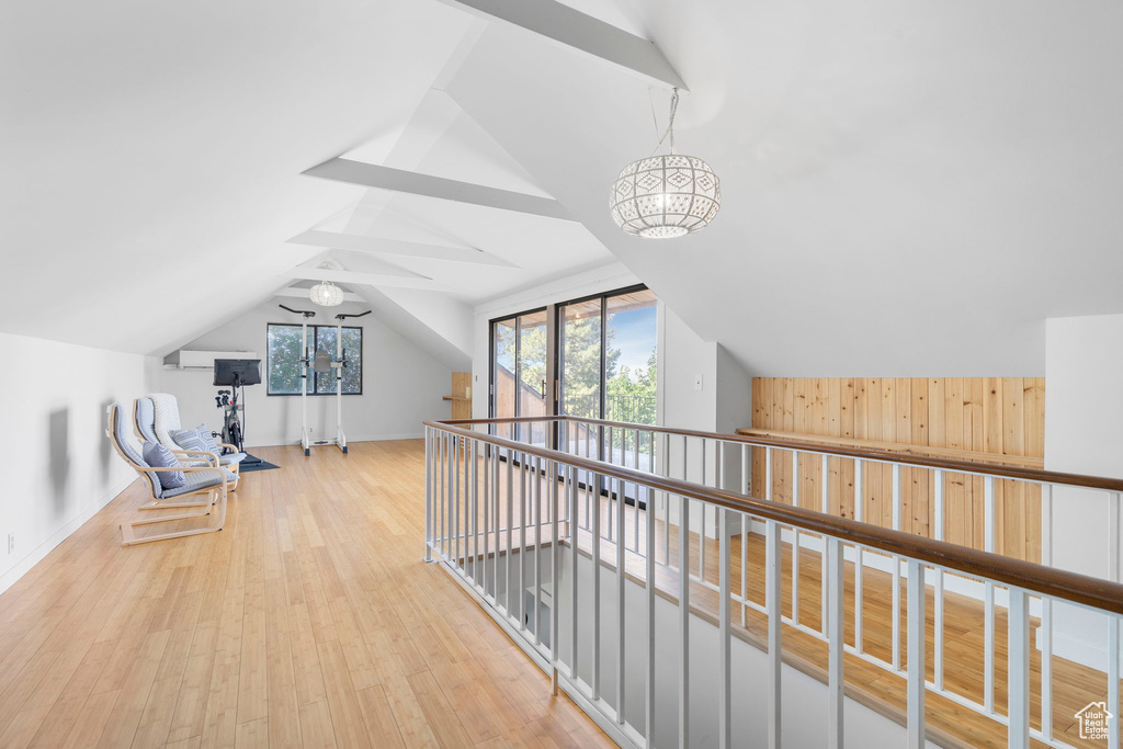 Hall featuring vaulted ceiling, wood finished floors, and wood walls
