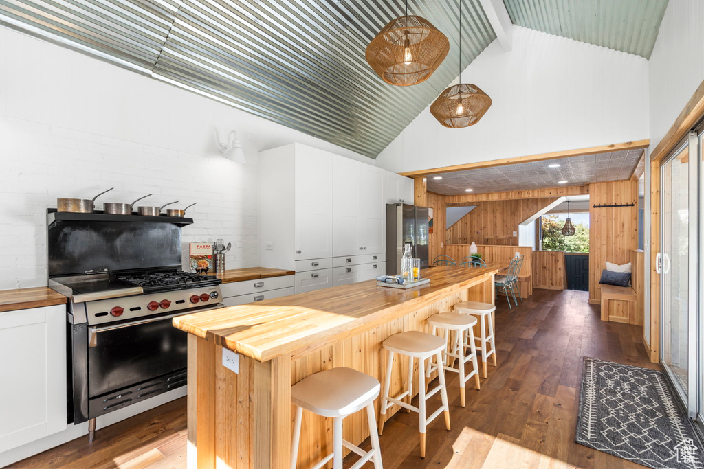 Kitchen featuring butcher block countertops, appliances with stainless steel finishes, wood walls, white cabinetry, and dark wood-style flooring