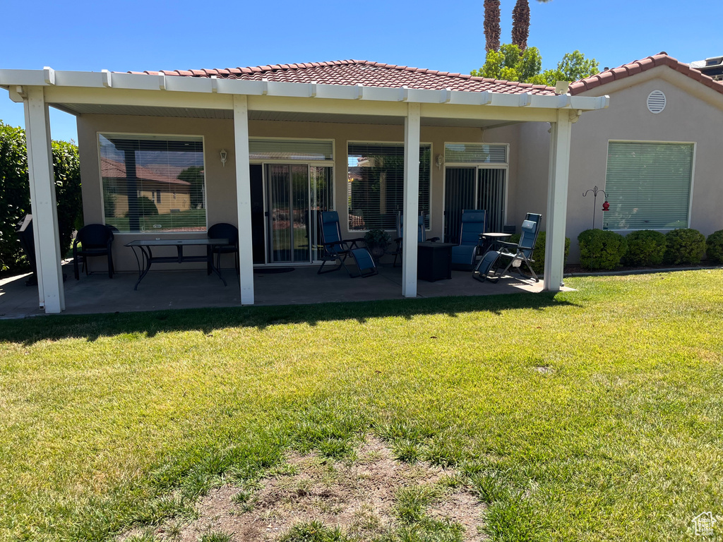 Rear view of house with a patio, stucco siding, a lawn, and a tile roof