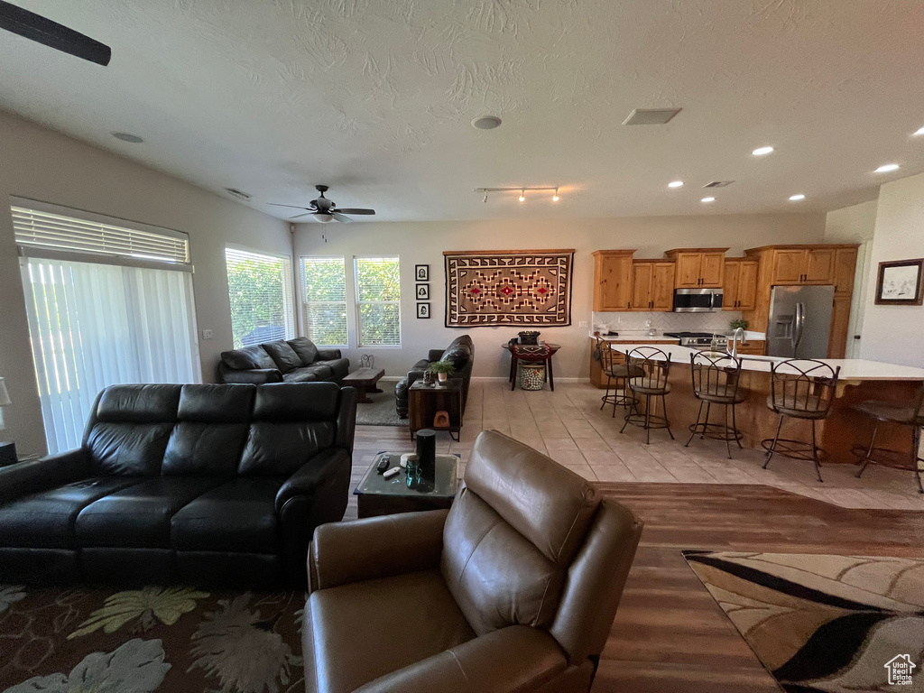 Living room with a ceiling fan, recessed lighting, light wood-type flooring, and a textured ceiling