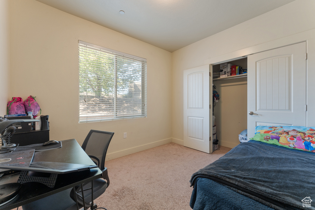 Carpeted bedroom with a desk and baseboards