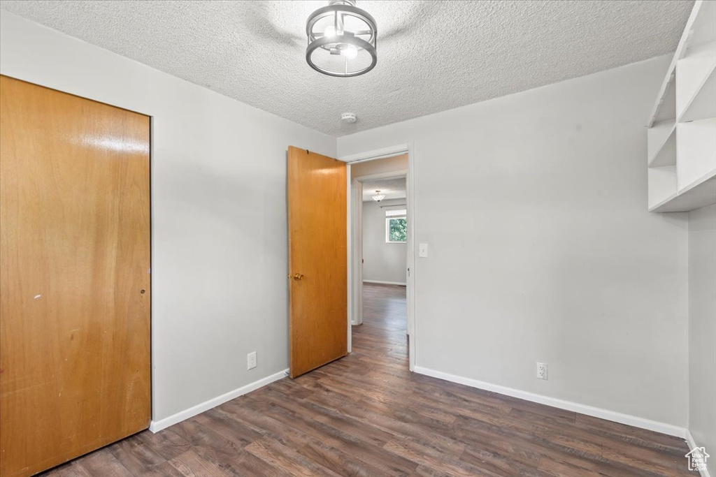 Unfurnished bedroom with dark wood-style flooring, a closet, and a textured ceiling