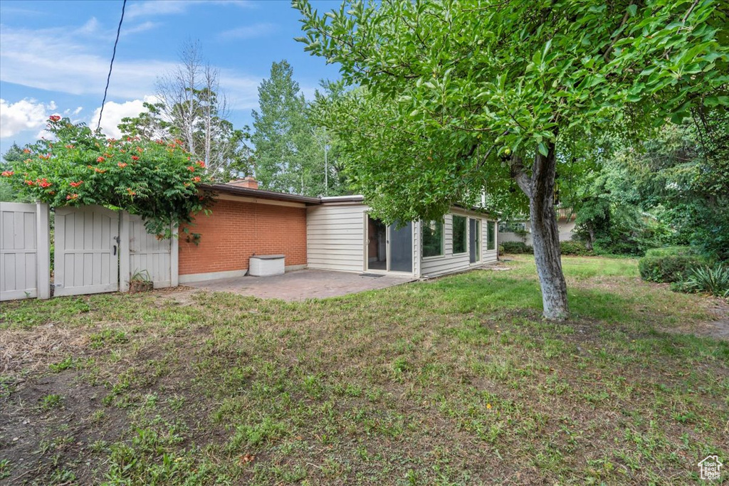 Rear view of property with a patio and a lawn
