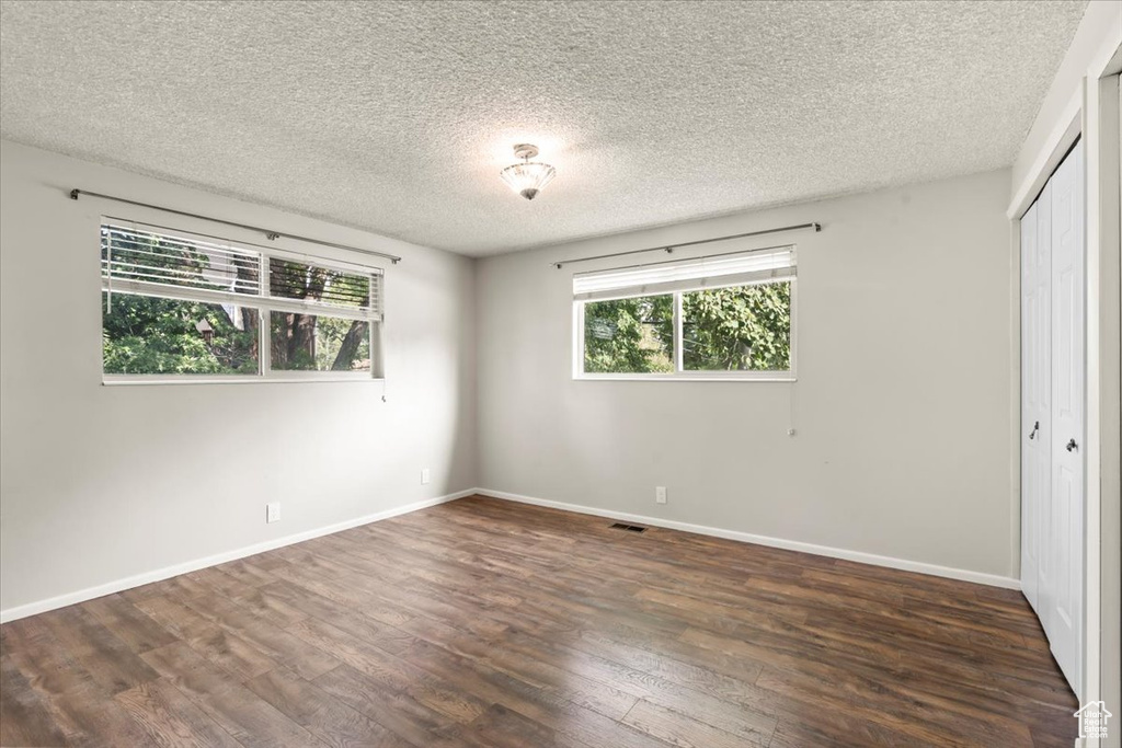 Unfurnished bedroom with wood finished floors, a closet, and a textured ceiling