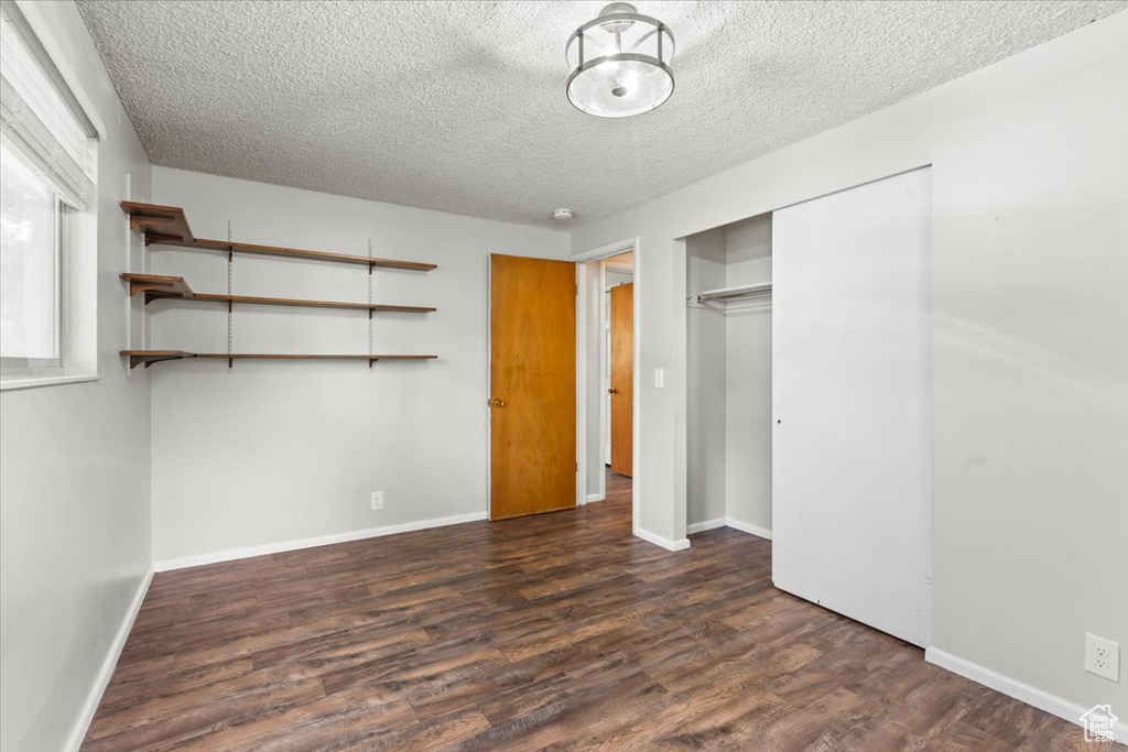 Unfurnished bedroom featuring a textured ceiling, wood finished floors, and a closet