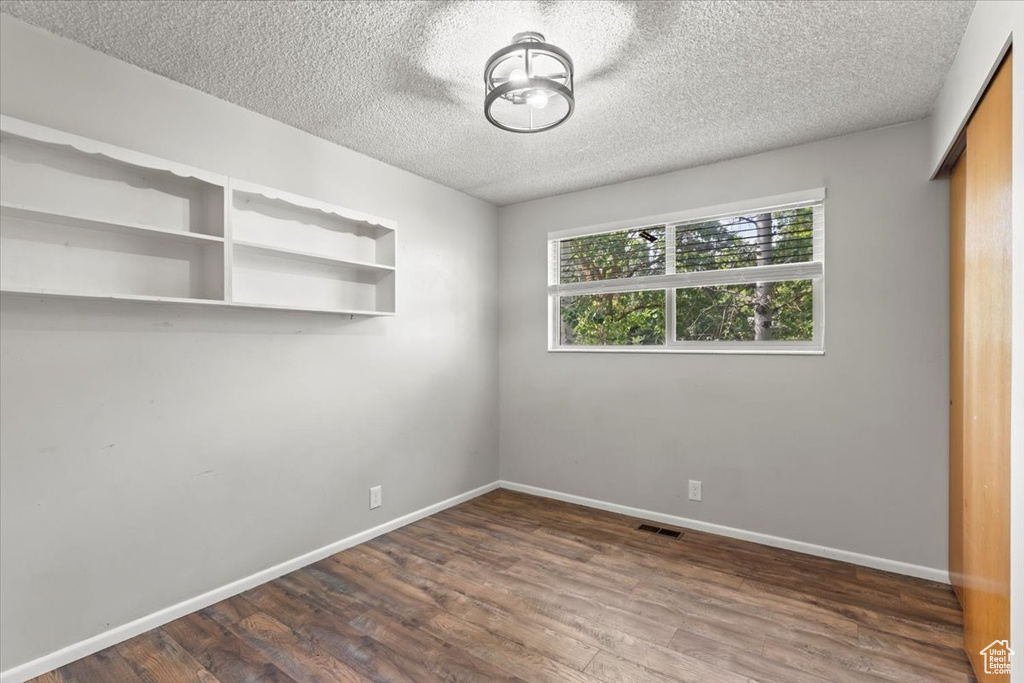 Unfurnished room featuring dark wood finished floors and a textured ceiling