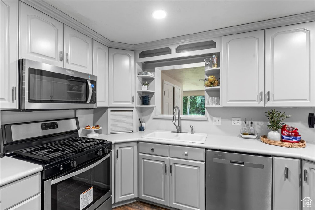 Kitchen with open shelves, stainless steel appliances, white cabinets, light countertops, and recessed lighting