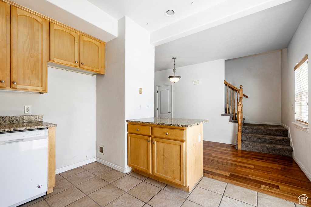 Kitchen with dishwasher, light tile patterned floors, light stone countertops, and light brown cabinets
