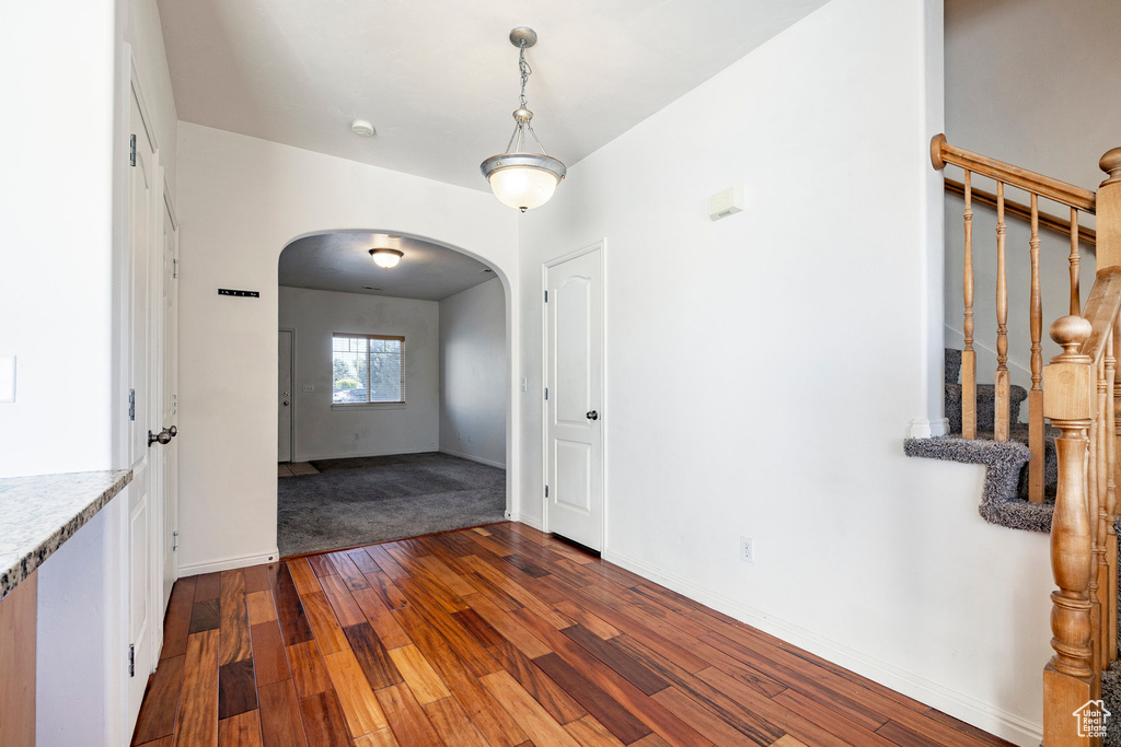 Unfurnished room with arched walkways, wood-type flooring, and stairs