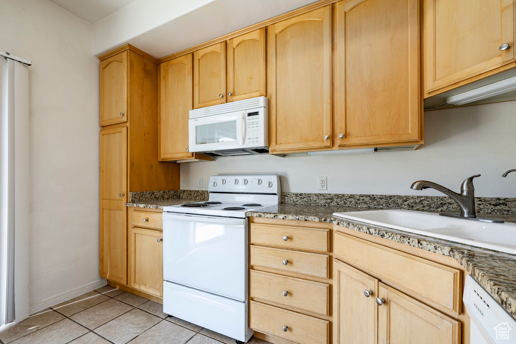 Kitchen with white appliances, light brown cabinetry, and light tile patterned flooring