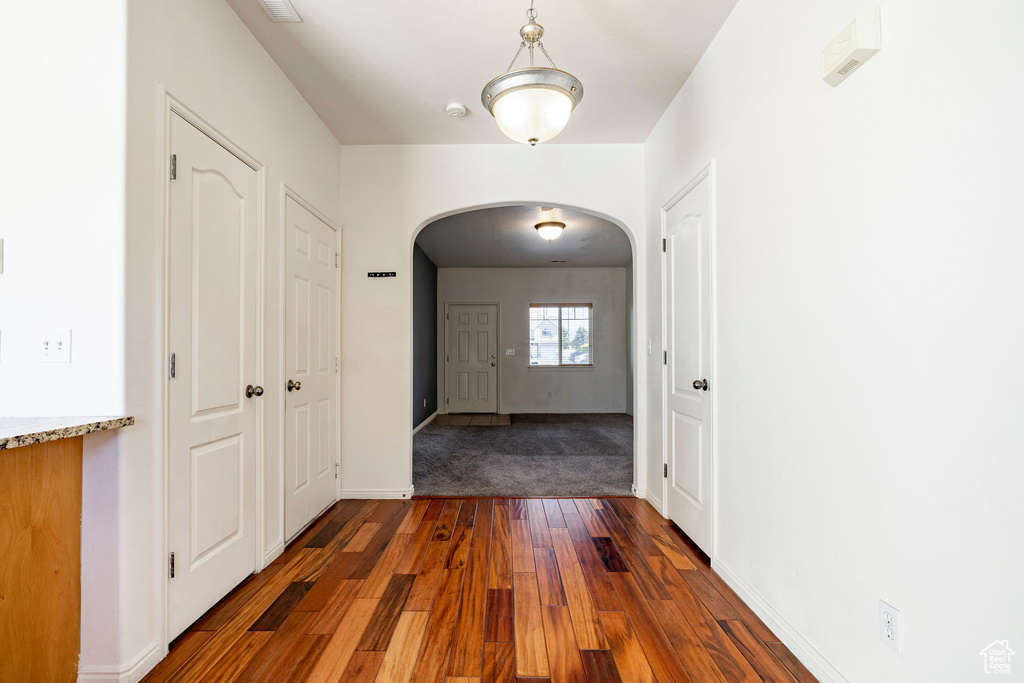 Entrance foyer with arched walkways and dark wood-style floors