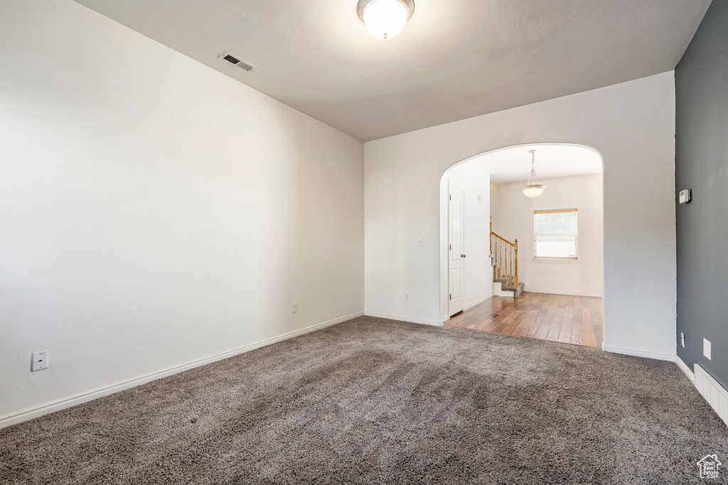 Empty room featuring carpet, arched walkways, and stairs