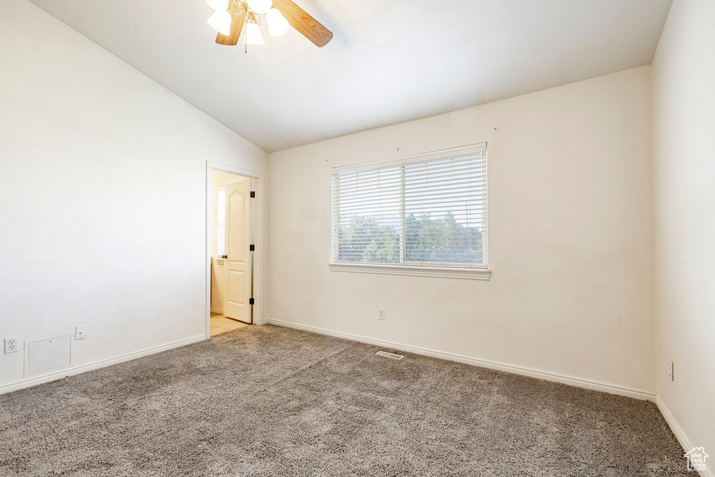 Empty room featuring carpet flooring, vaulted ceiling, and ceiling fan