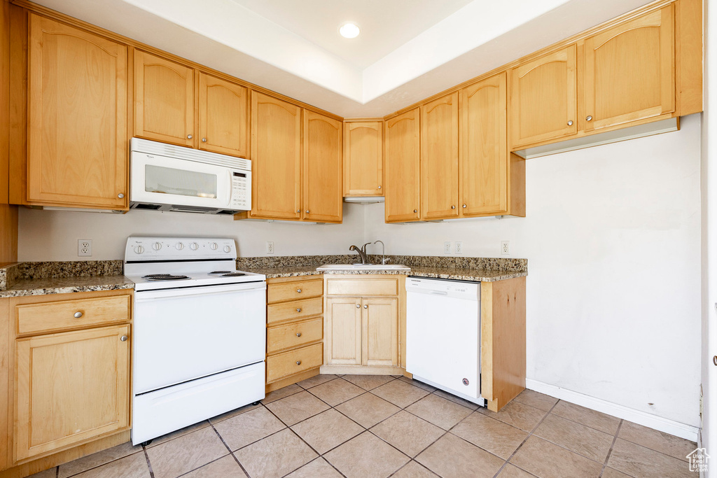 Kitchen with white appliances, light brown cabinetry, light tile patterned flooring, stone countertops, and recessed lighting
