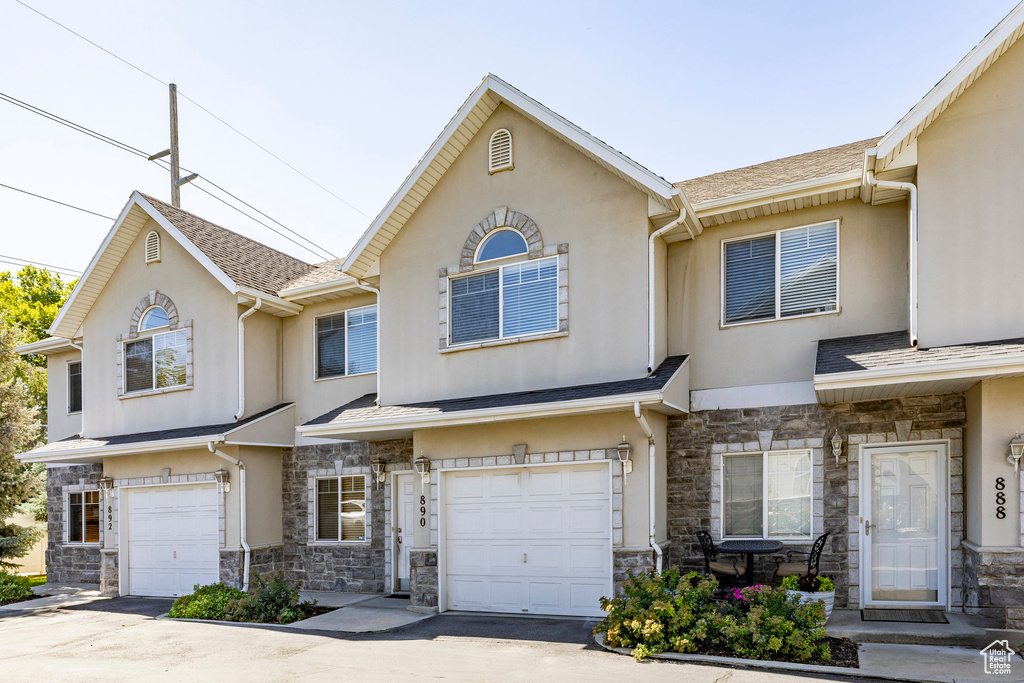 Traditional-style home featuring an attached garage, stone siding, stucco siding, and driveway