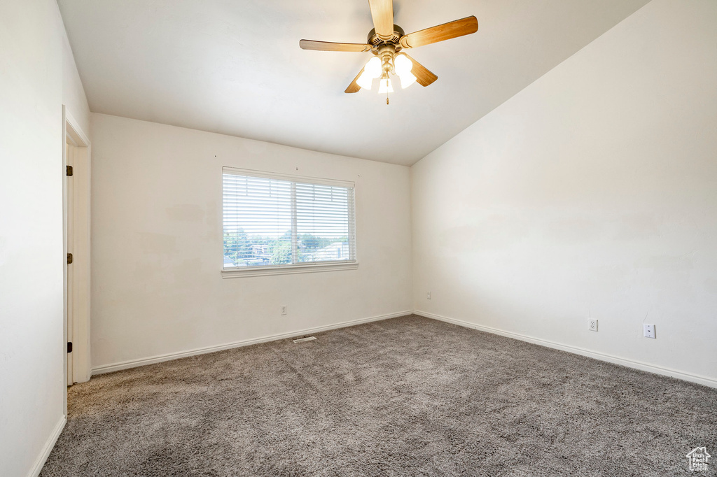 Carpeted spare room with vaulted ceiling and ceiling fan