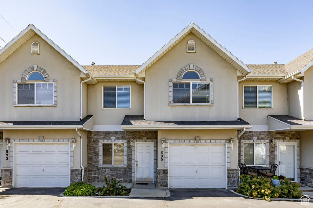 Traditional home featuring an attached garage, stone siding, and driveway