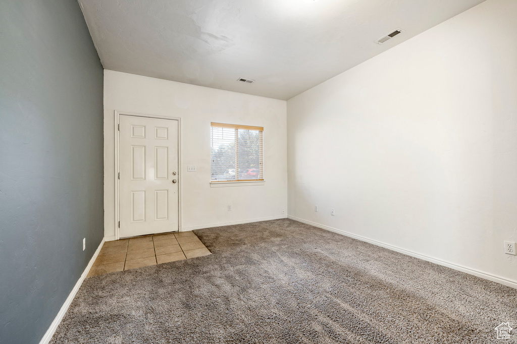 Carpeted empty room featuring tile patterned flooring and baseboards