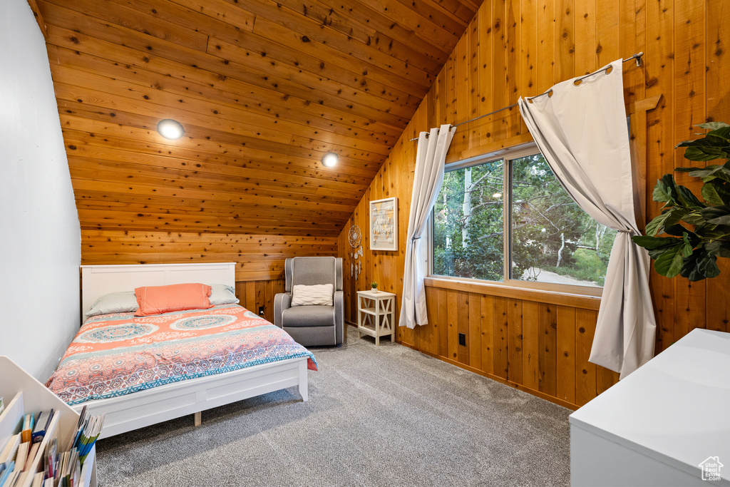 Bedroom with lofted ceiling, wood walls, carpet flooring, and wooden ceiling