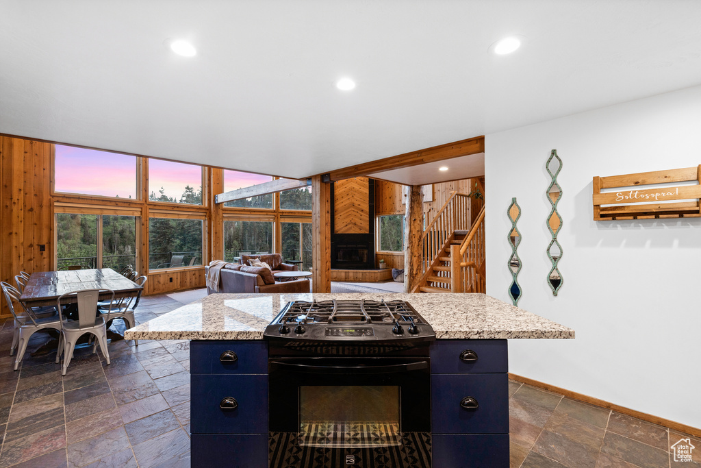 Kitchen featuring black gas stove, blue cabinets, stone tile floors, open floor plan, and recessed lighting