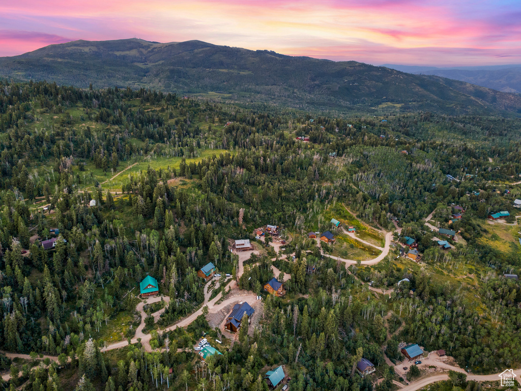 Aerial overview of property's location featuring a mountainous background and a heavily wooded area