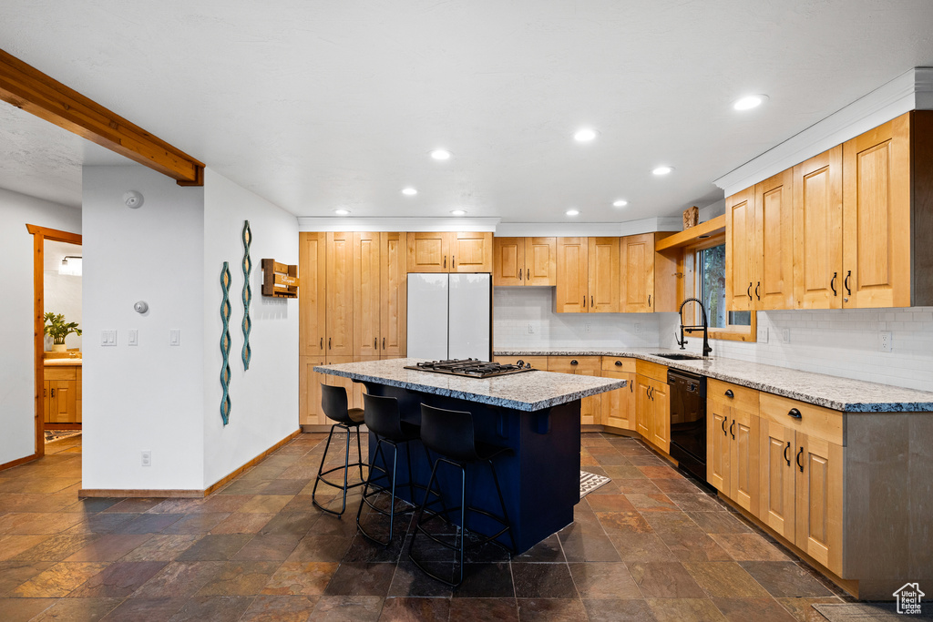 Kitchen with a kitchen breakfast bar, a center island, recessed lighting, freestanding refrigerator, and light stone countertops