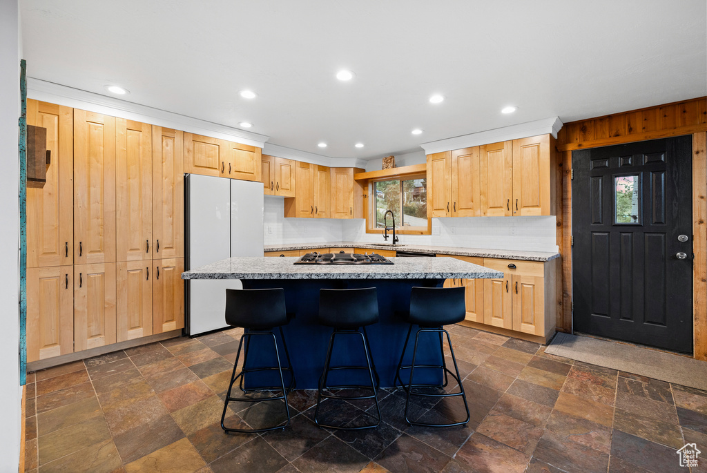 Kitchen with stone tile flooring, light brown cabinetry, plenty of natural light, freestanding refrigerator, and recessed lighting