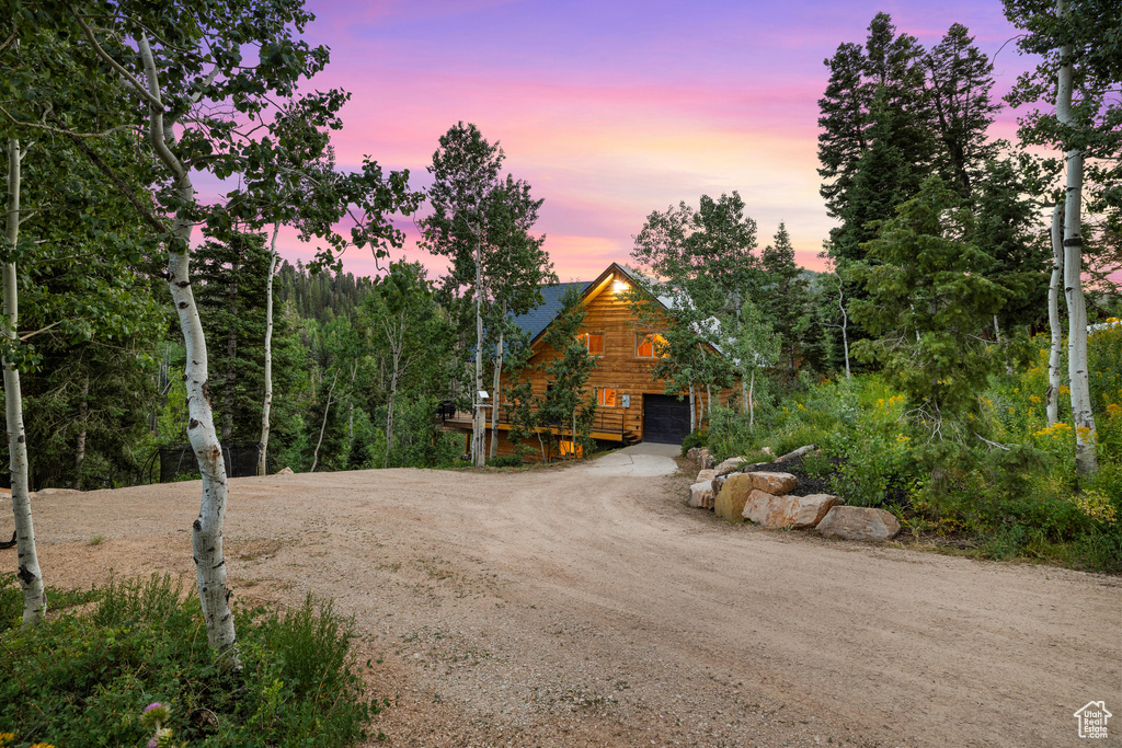 View of front of house with driveway, a garage, and log siding