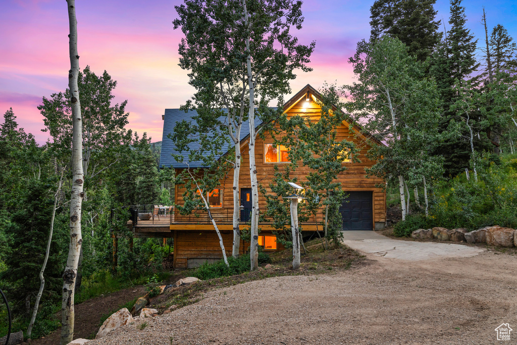 Rustic home with driveway, a garage, and a deck