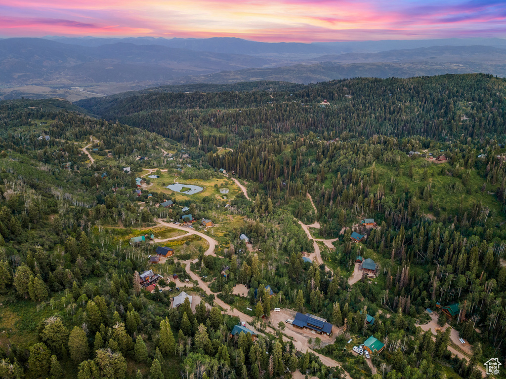 Aerial view of property and surrounding area with a heavily wooded area and a mountain backdrop