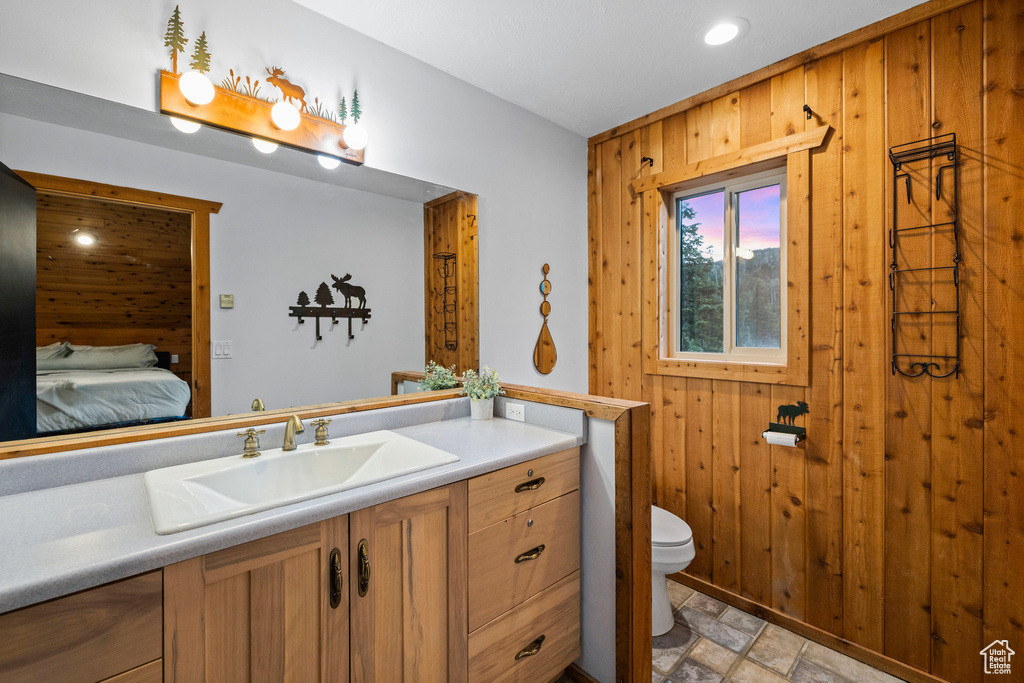 Bathroom featuring vanity, stone finish flooring, ensuite bath, and wooden walls