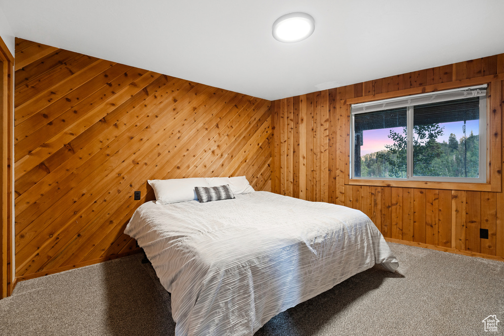 Carpeted bedroom featuring wood walls
