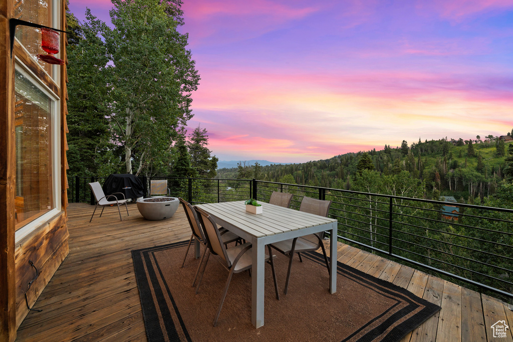 Deck at dusk with outdoor dining area and a forest view