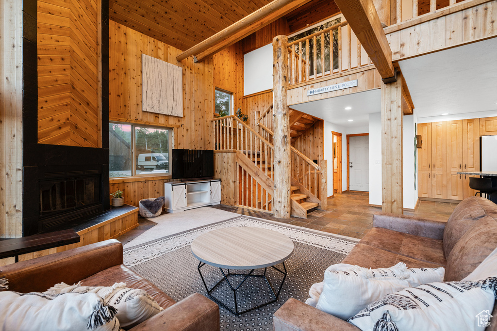 Living area with wood walls, stairs, a high ceiling, stone finish floors, and a fireplace