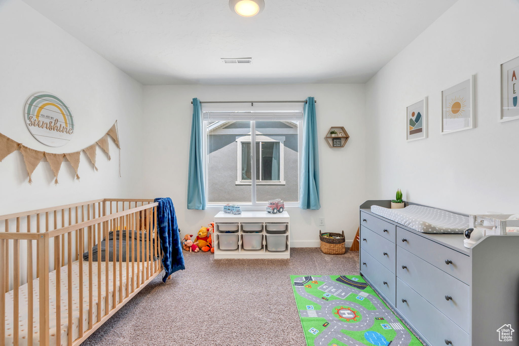 Carpeted bedroom featuring a crib