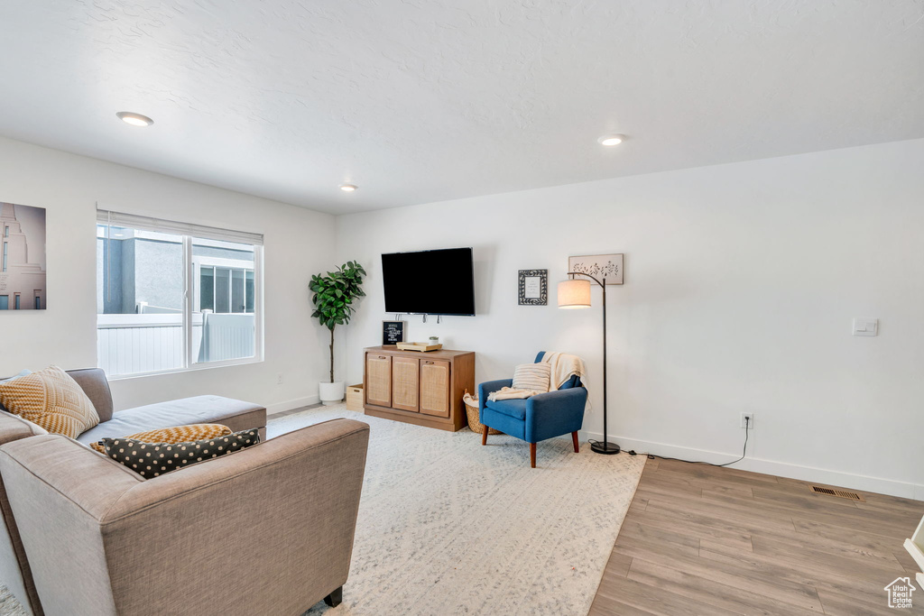 Living room with light wood-style flooring and recessed lighting